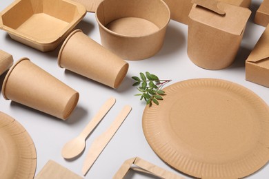 Eco friendly food packaging. Paper containers, tableware and green twigs on light grey background