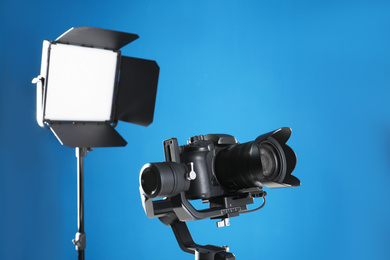 Professional video camera and lighting equipment on blue background