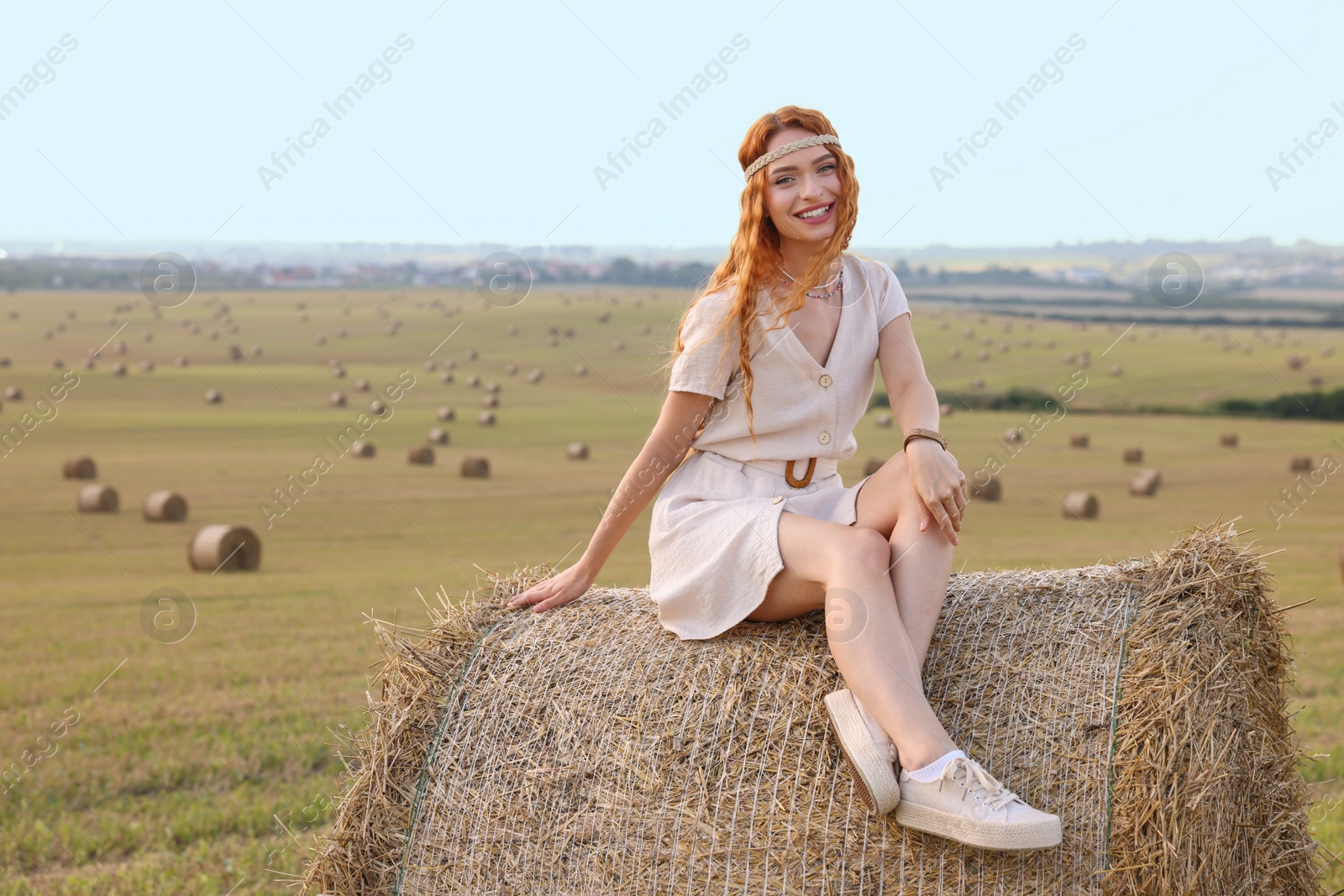 Photo of Beautiful hippie woman on hay bale in field, space for text