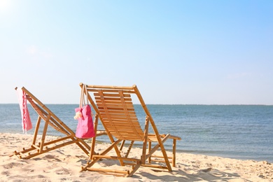 Empty wooden sunbeds and beach accessories on sandy shore