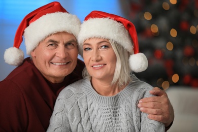 Happy mature couple in Santa hats at home. Christmas celebration