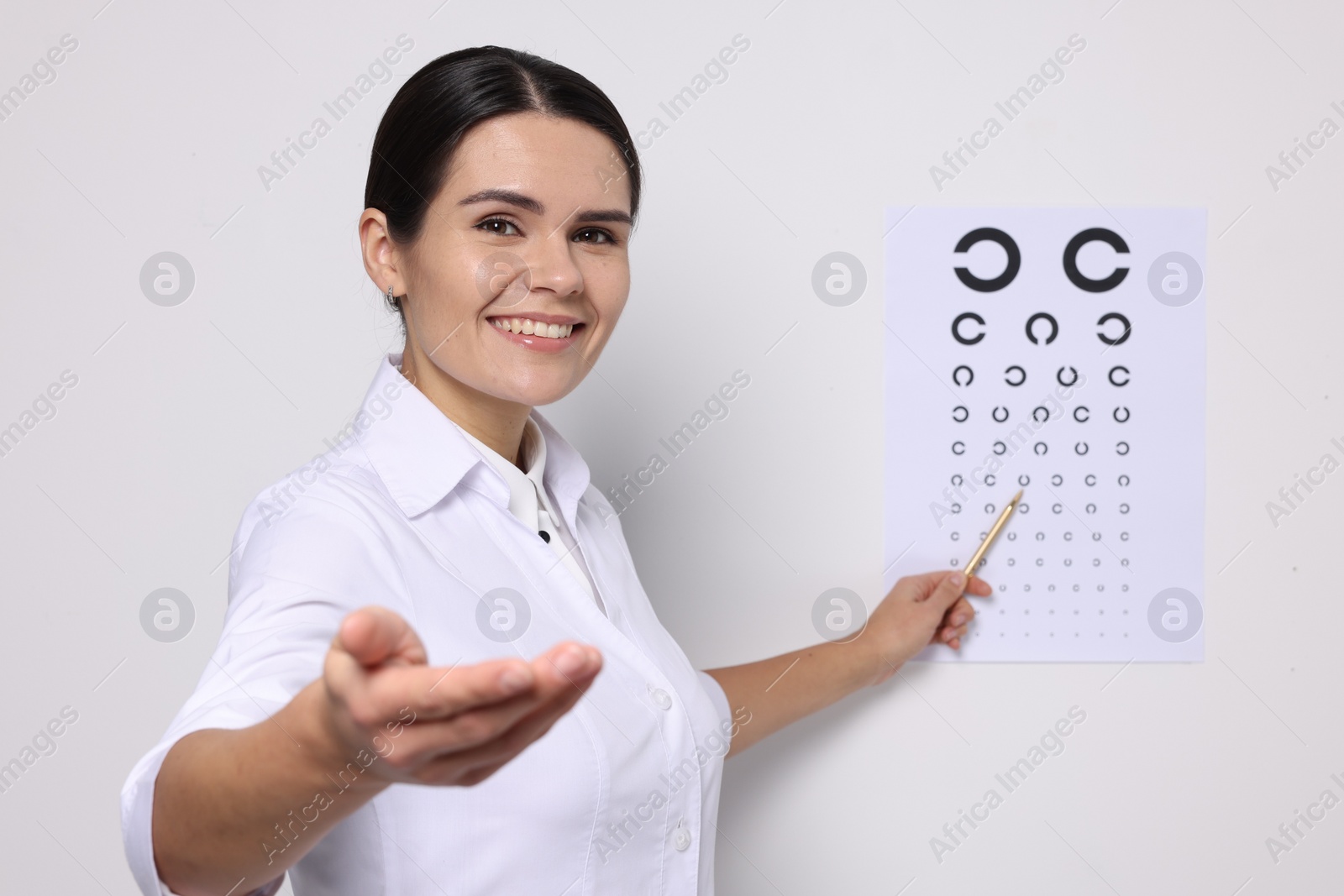 Photo of Ophthalmologist pointing at vision test chart on white wall