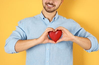 Man holding decorative heart on color background, closeup