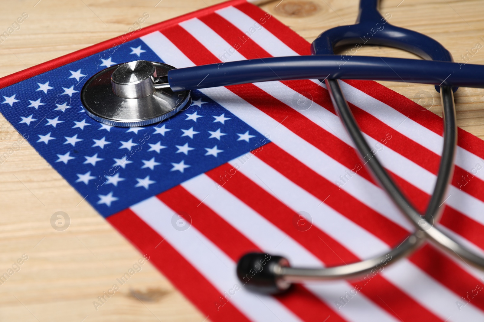 Photo of Stethoscope and USA flag on wooden table, closeup. Health care concept