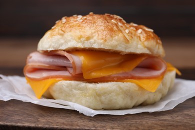 Photo of Delicious bagel with ham and cheese on wooden table, closeup