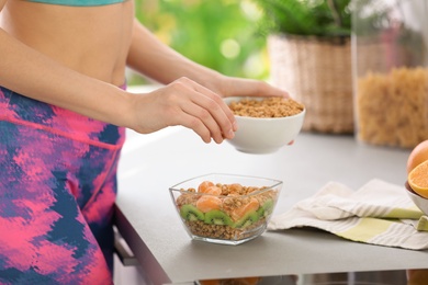 Photo of Young woman in fitness clothes preparing healthy breakfast at home, closeup