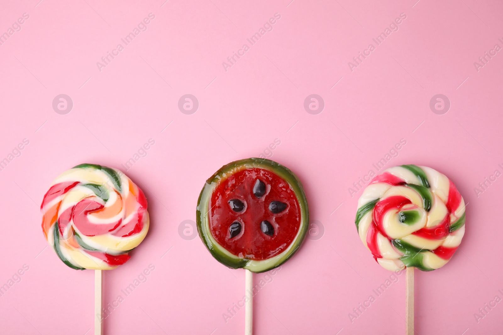 Photo of Different colorful lollipops on pink background, flat lay. Space for text