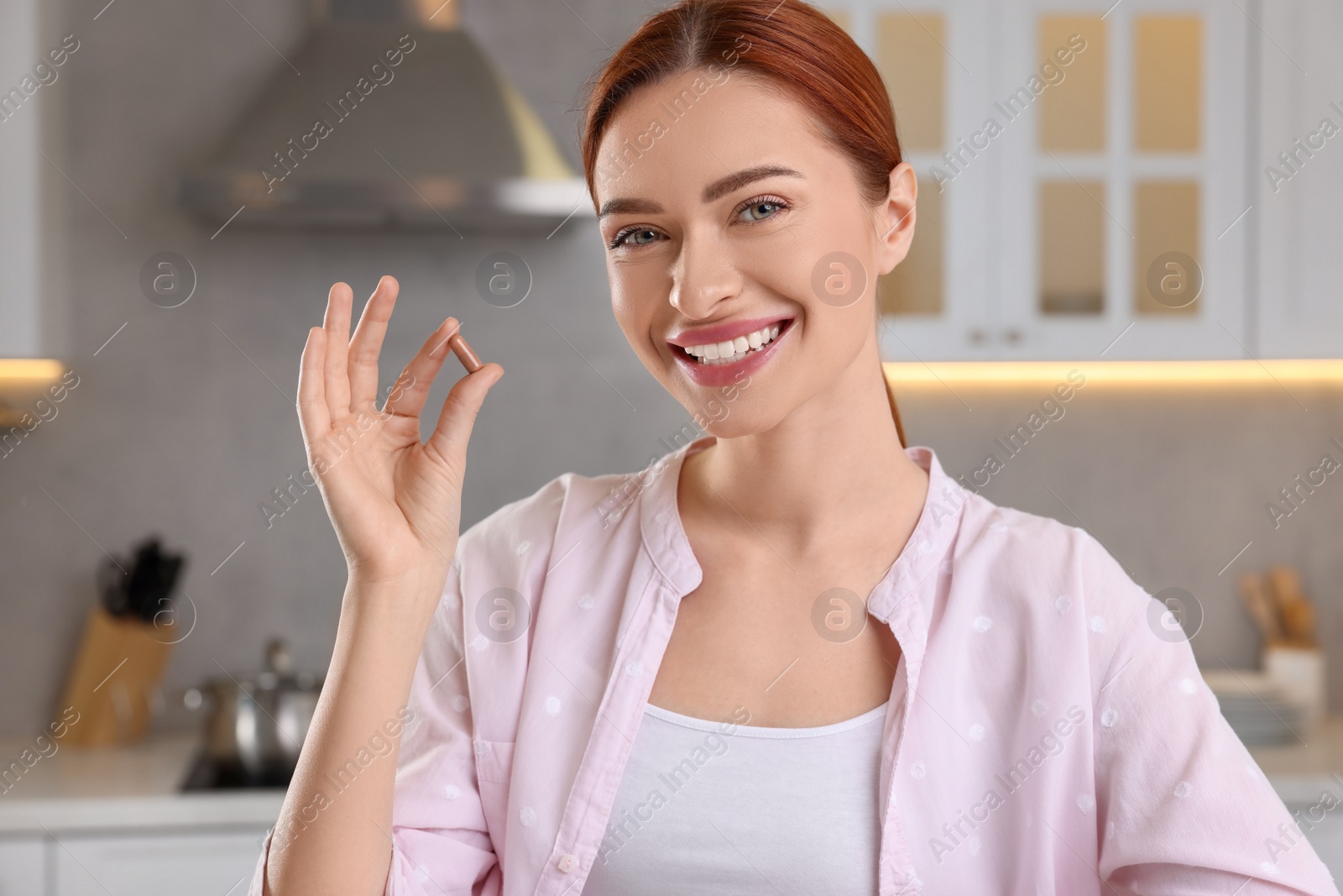 Photo of Beautiful young woman with vitamin pill at home