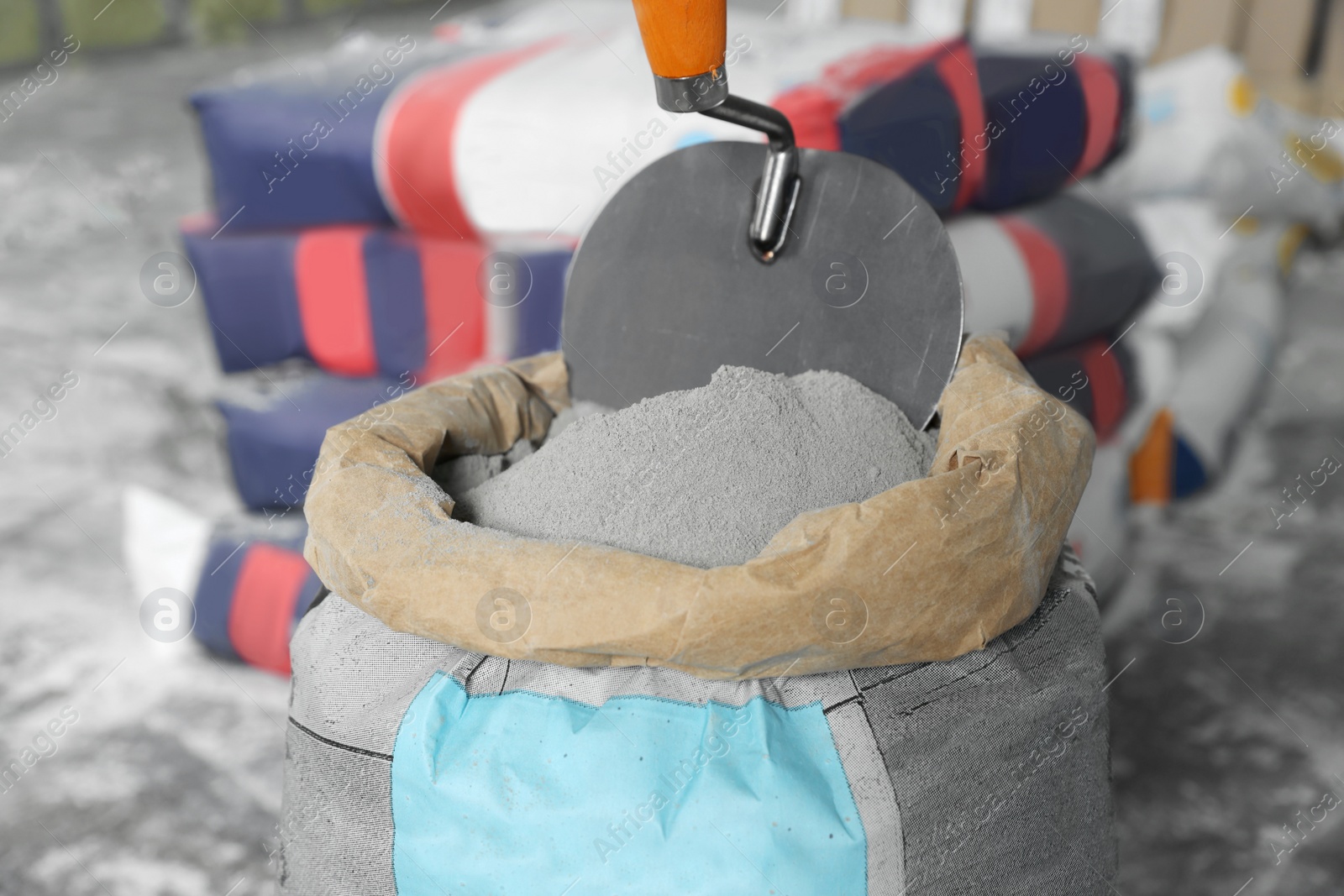 Photo of Cement powder and trowel put in bag indoors, closeup