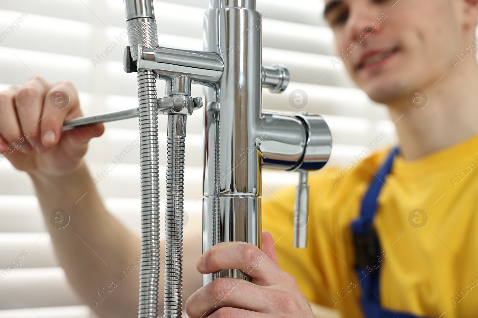 Photo of Plumber repairing faucet with spanner in bathroom, closeup