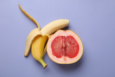 Photo of Banana and half of grapefruit on violet background, flat lay. Sex concept