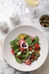 Photo of Delicious salad with vegetables and olives served on white marble table, flat lay