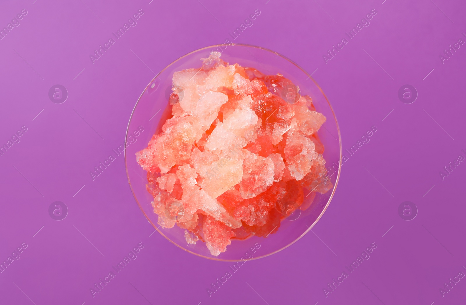 Photo of Shaving ice in martini glass on violet background, top view