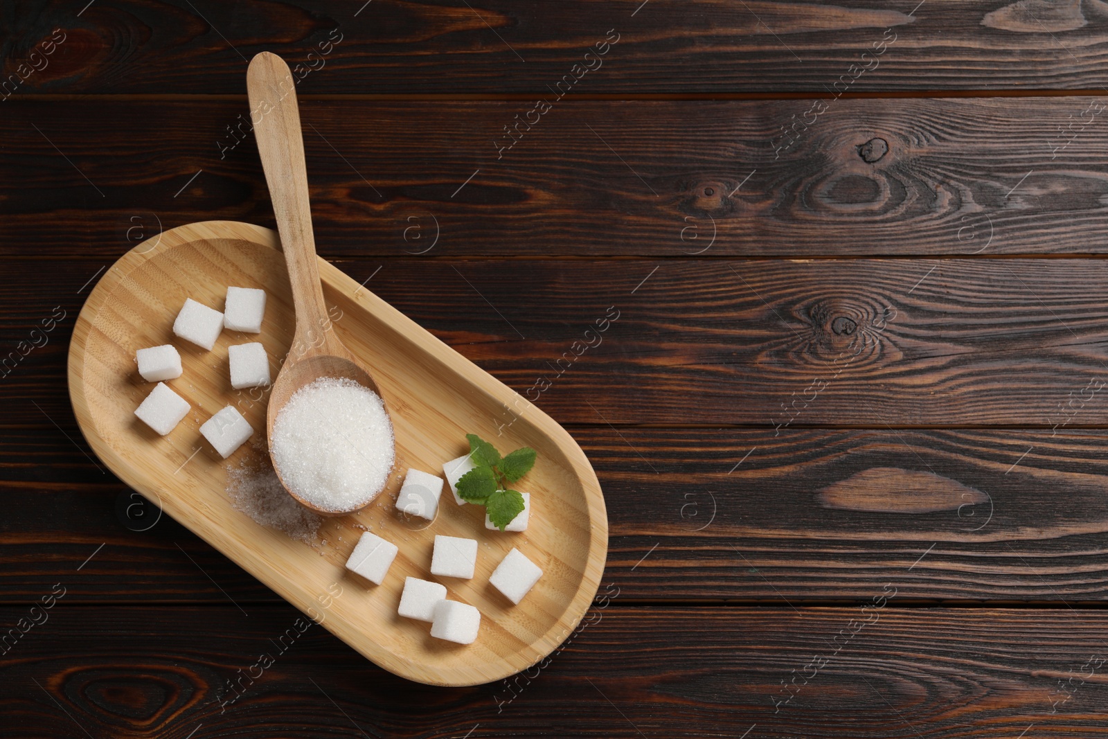 Photo of Tray and spoon with white sugar on wooden table, top view. Space for text