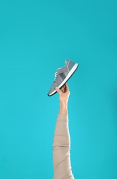 Photo of Young man holding comfortable shoe on light blue background, closeup