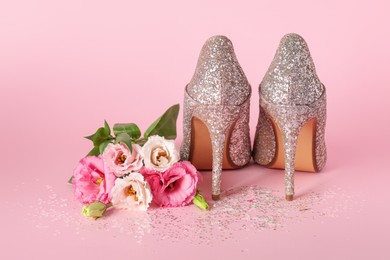 Photo of Stylish women's high heeled shoes and beautiful flowers on pink background
