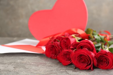 Photo of Beautiful red roses and heart shaped box on grey table, space for text. Valentine's Day celebration