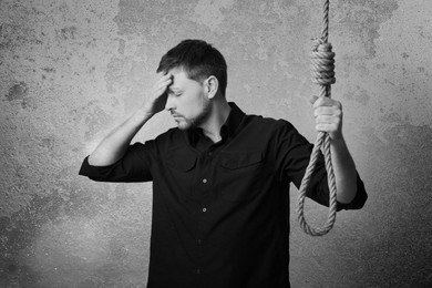 Image of Depressed man with rope noose near wall. Suicide concept