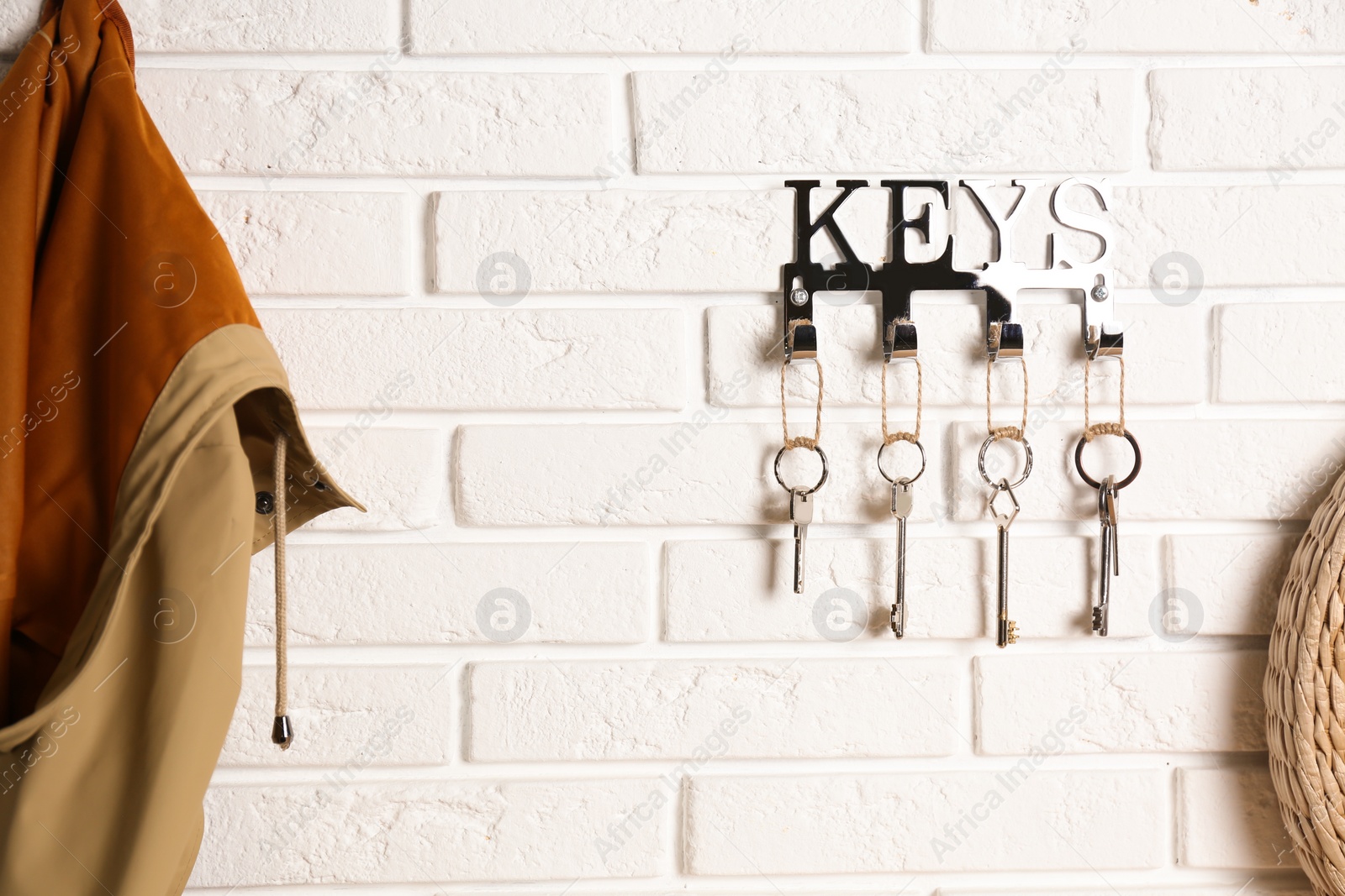 Photo of Metal key holder on white brick wall indoors