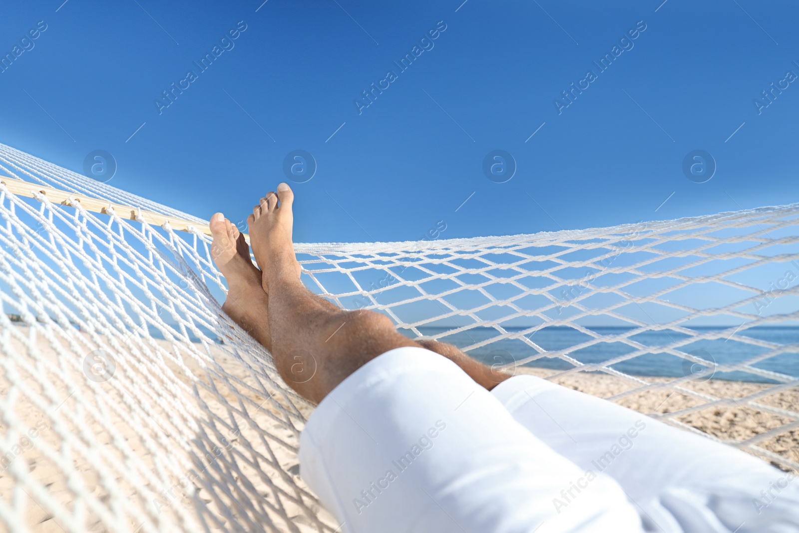Photo of Man relaxing in hammock on beach, closeup