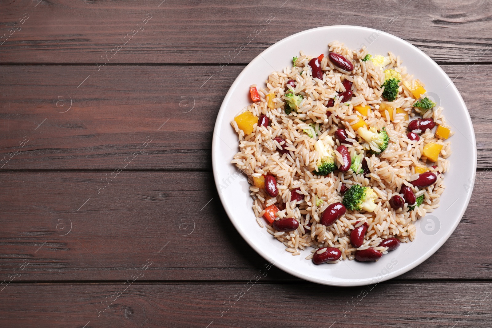 Photo of Delicious rice with beans on wooden table, top view. Space for text