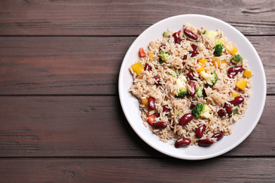 Photo of Delicious rice with beans on wooden table, top view. Space for text