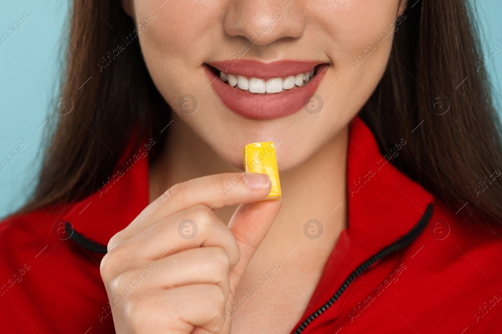 Photo of Woman with bubble gum on light blue background, closeup