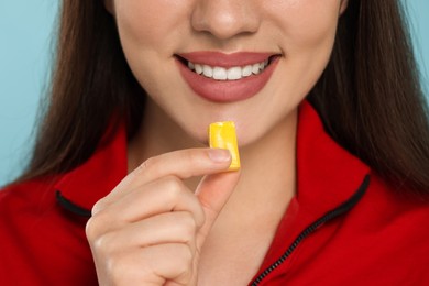 Woman with bubble gum on light blue background, closeup