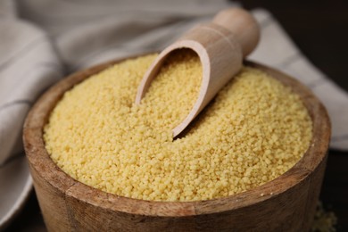 Bowl and scoop with raw couscous on table, closeup