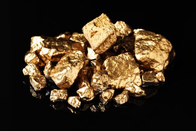 Pile of shiny gold nuggets on black background