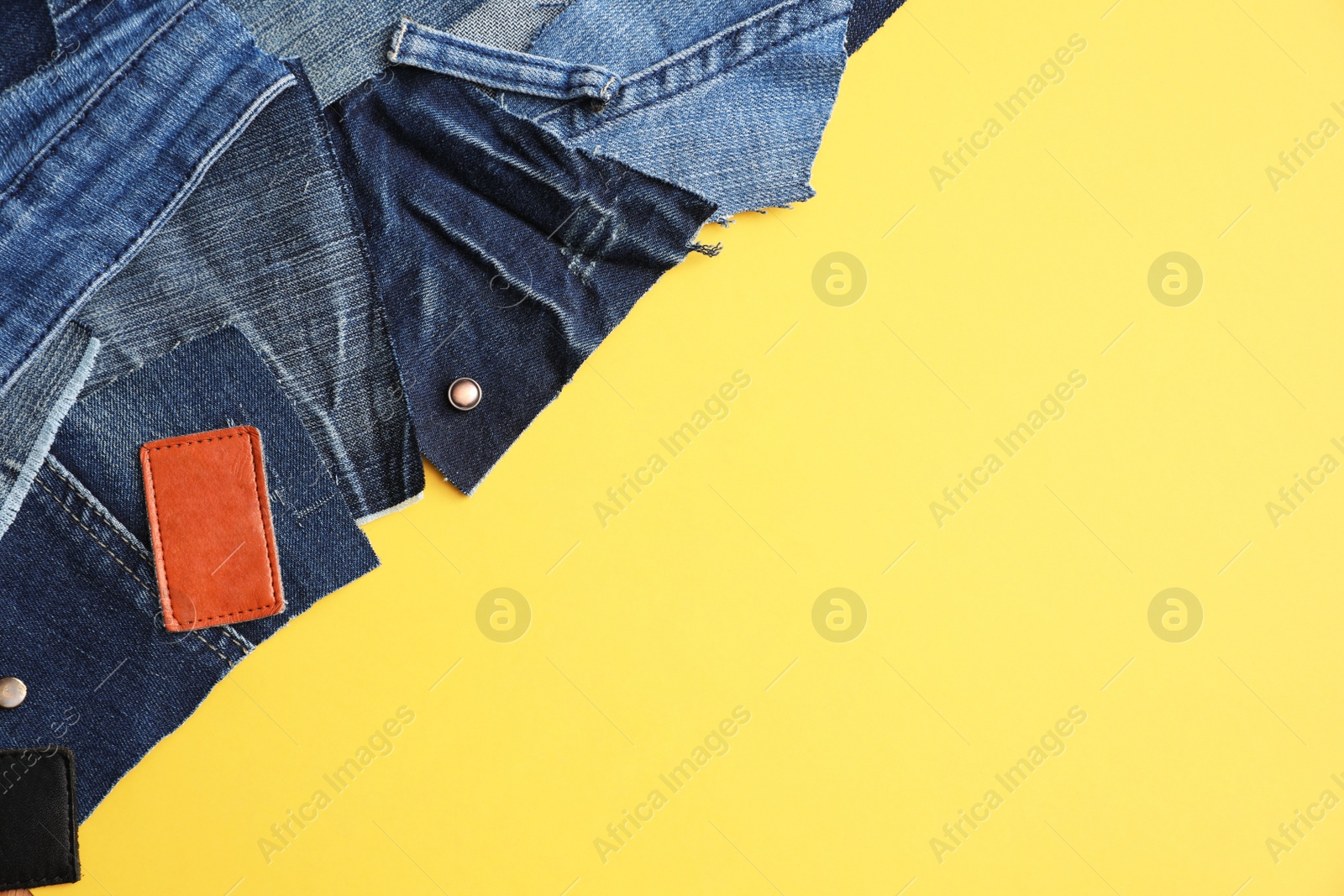 Photo of Flat lay composition with patches of old jeans on yellow background. Space for text