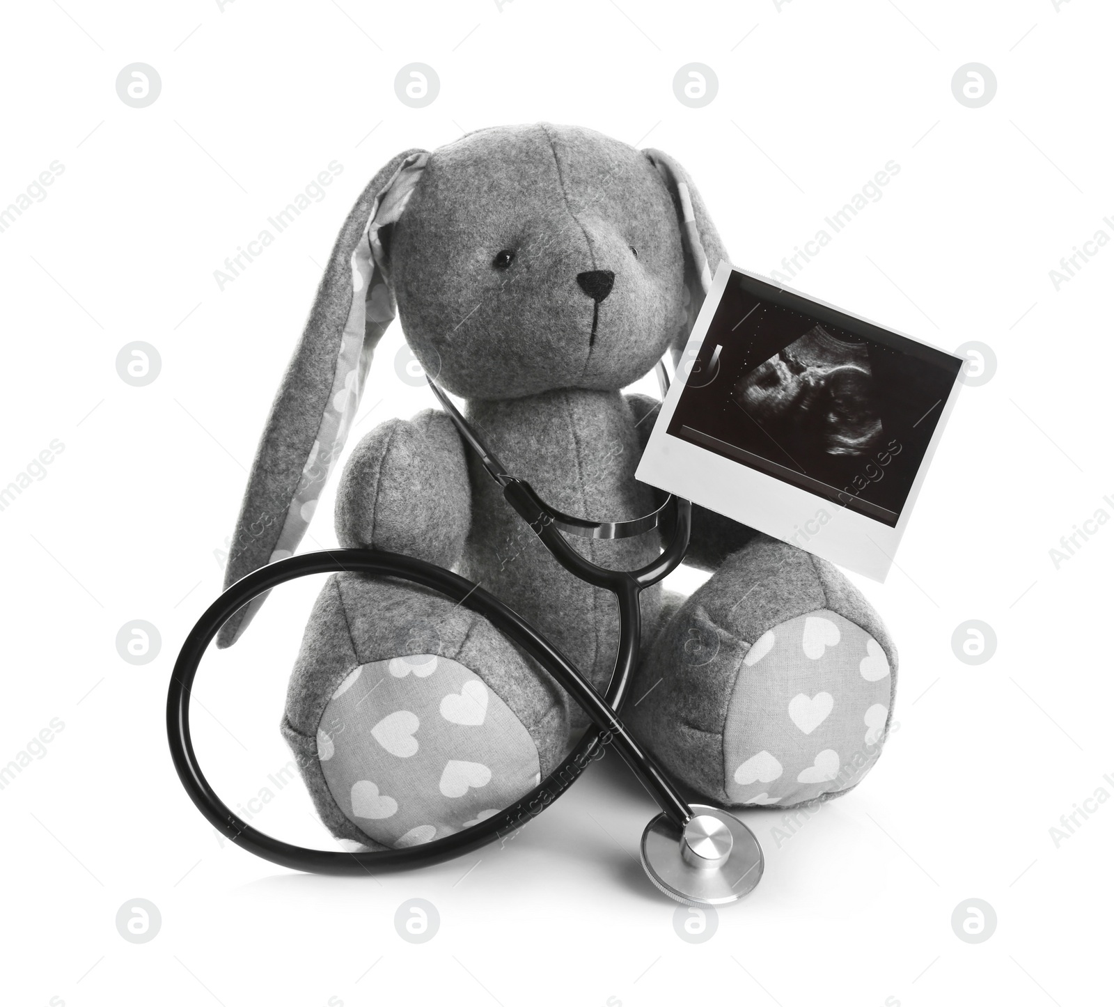 Photo of Ultrasound photo of baby and toy rabbit on white background. Concept of pregnancy