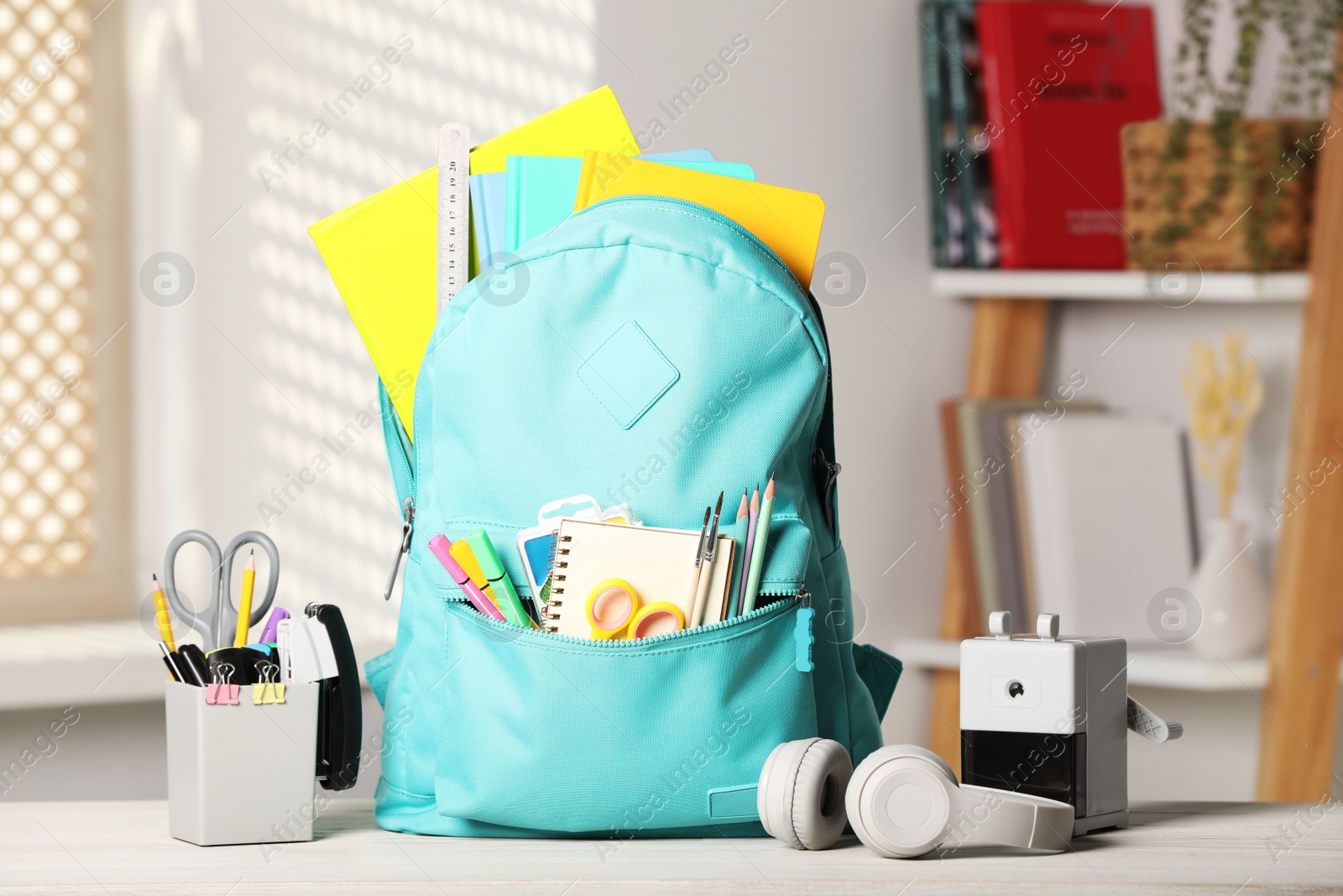 Photo of Turquoise backpack and school stationery on table indoors