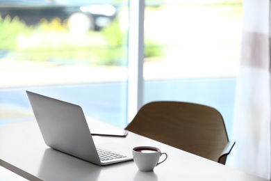 Photo of Comfortable workplace with modern laptop on desk in home office, space for text