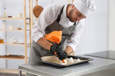 Photo of Pastry chef preparing meringues at table in kitchen