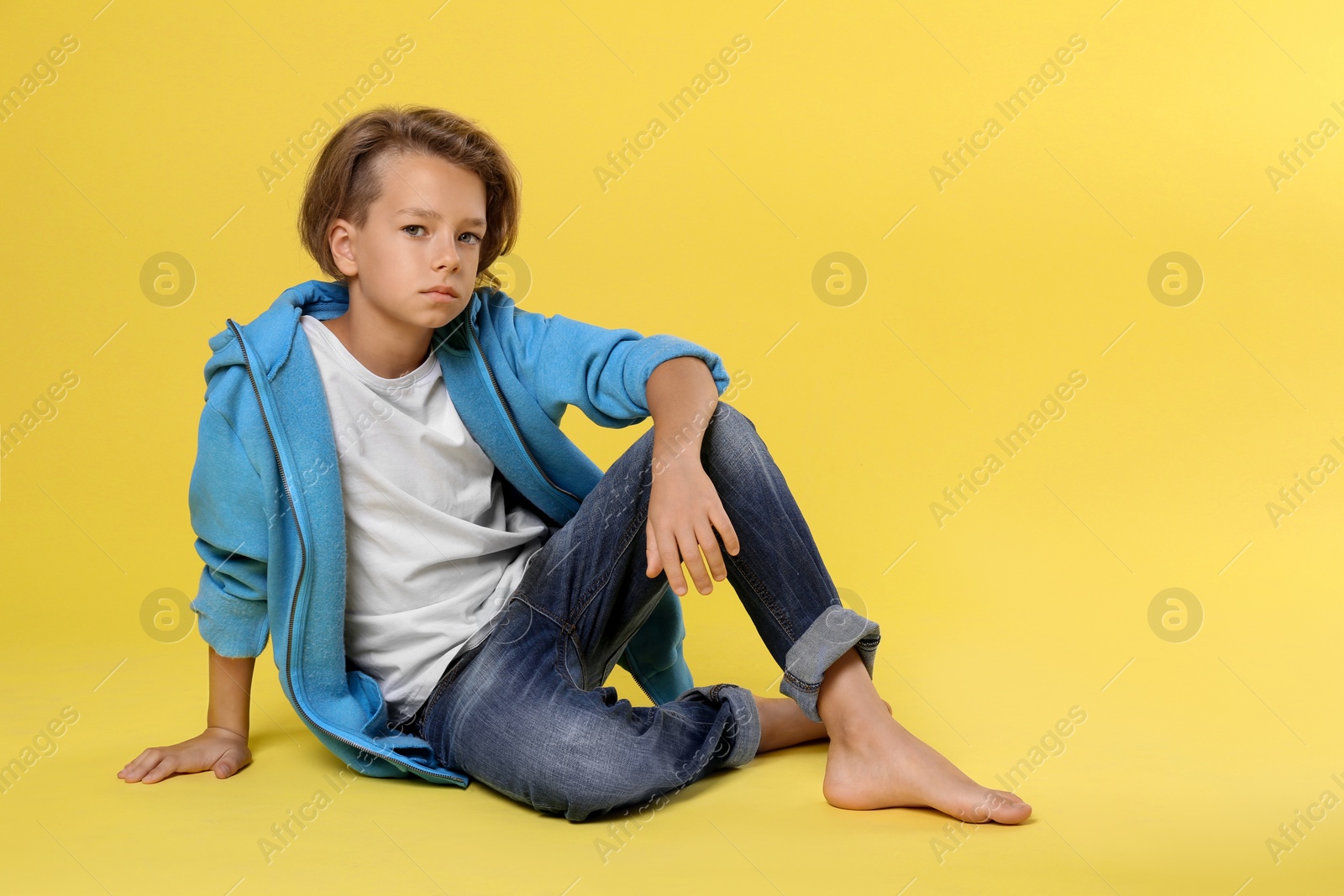 Photo of Cute little boy in casual outfit on yellow background. Space for text