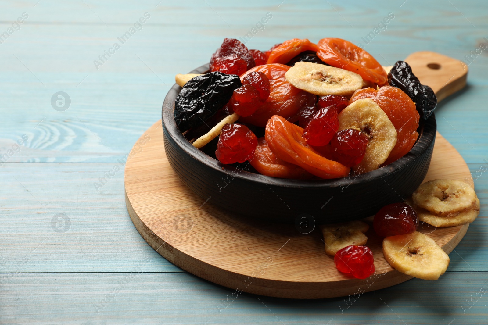 Photo of Mix of delicious dried fruits on light blue wooden table