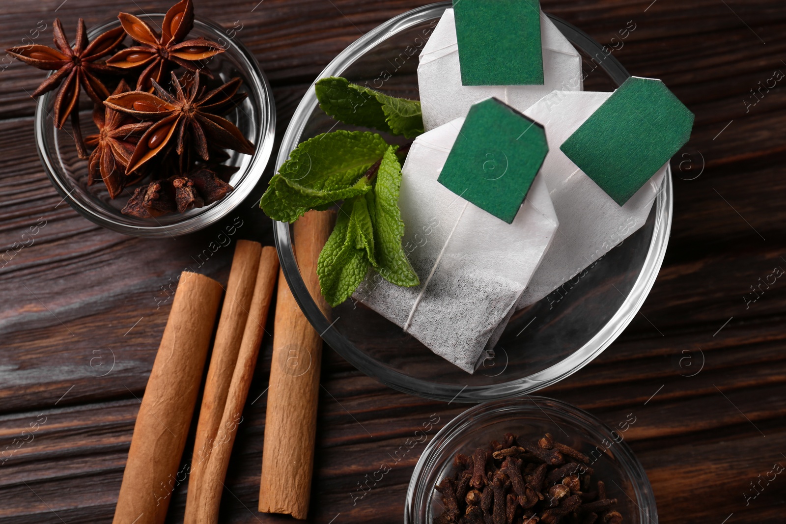 Photo of Tea bags and ingredients on wooden table, flat lay