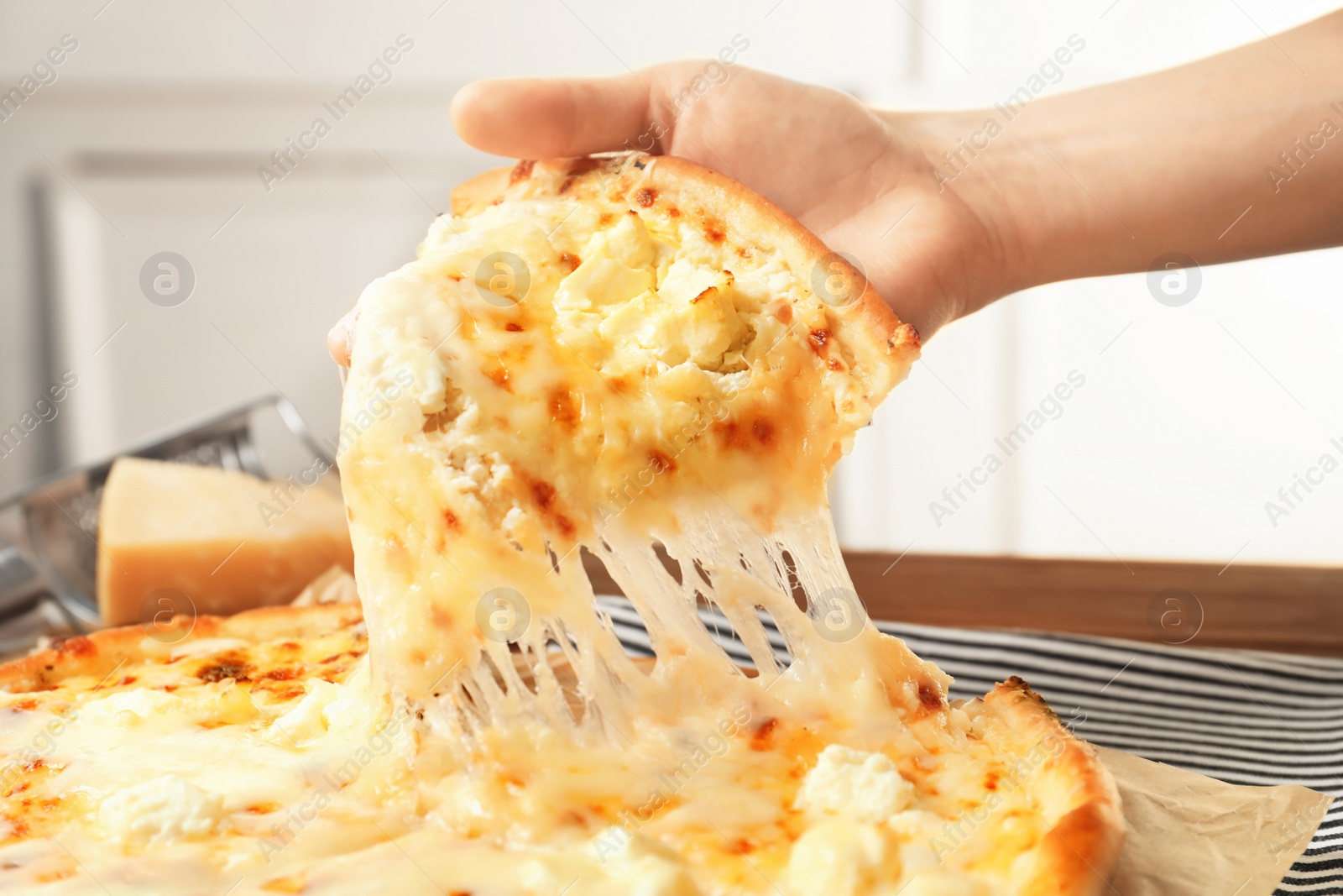 Photo of Woman holding slice of delicious hot pizza over table, closeup