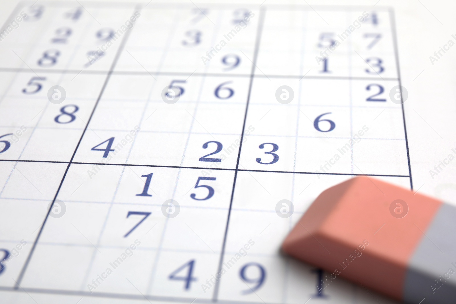 Photo of Sudoku puzzle grid and eraser, closeup view