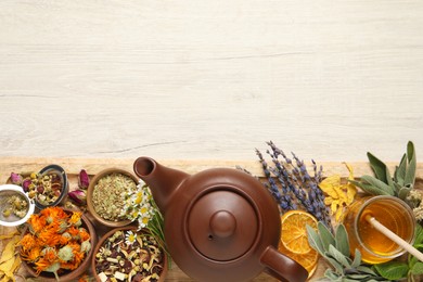 Photo of Clay teapot, honey and different dried herbs on white wooden table, top view. Space for text