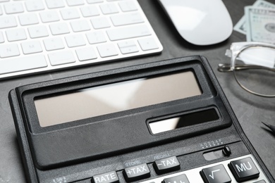 Photo of Calculator and keyboard on dark grey table, closeup. Tax accounting