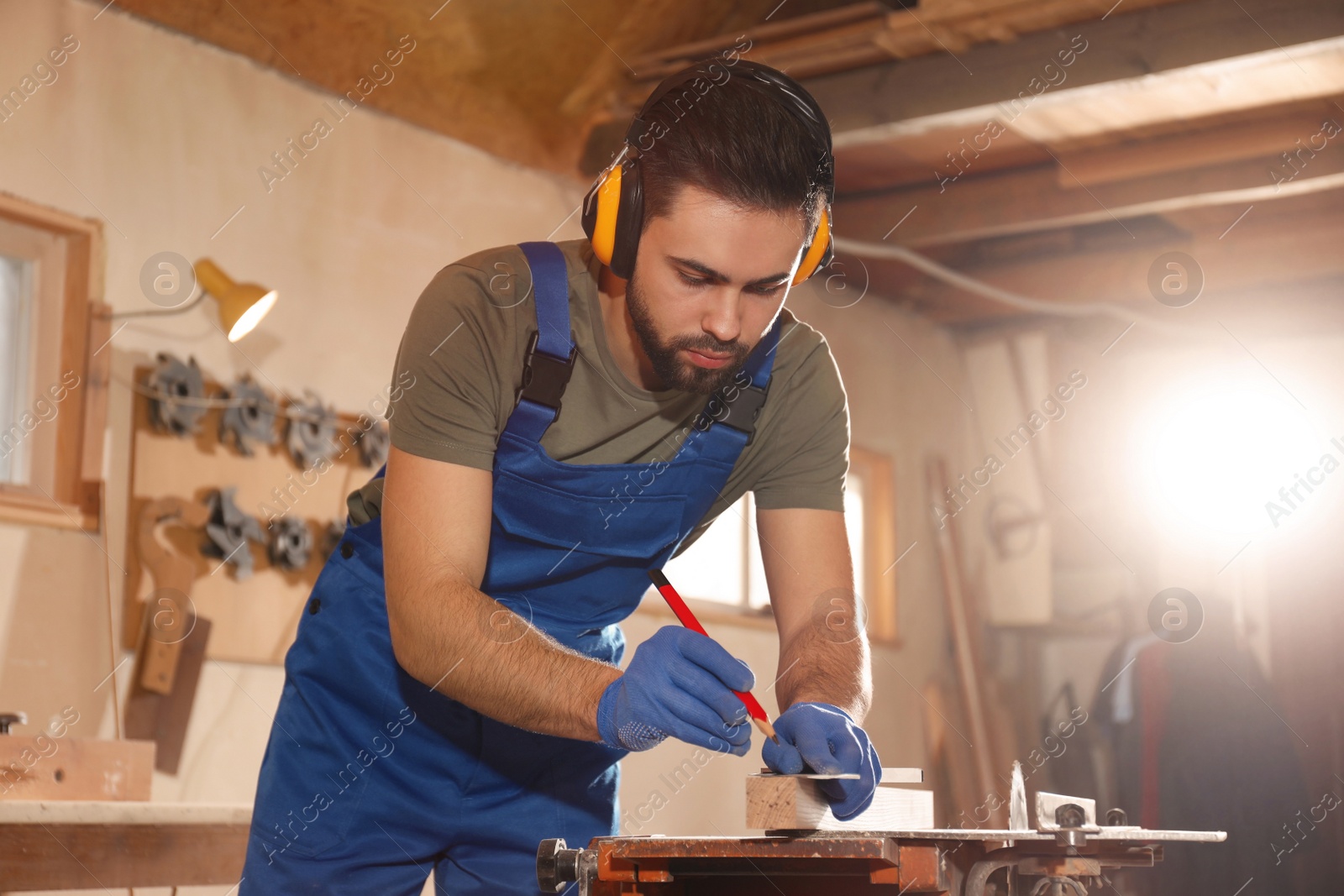 Photo of Professional carpenter making mark on wooden bar in workshop