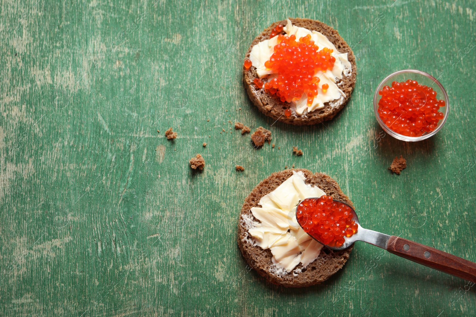 Photo of Delicious sandwiches with red caviar on wooden background, top view