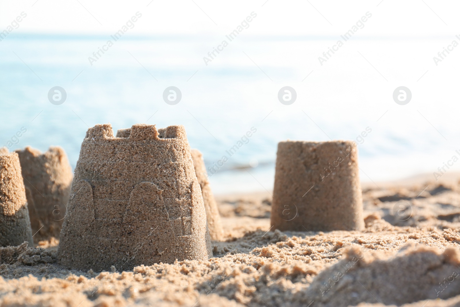 Photo of View of beach with little sand figures near sea on sunny summer day. Space for text