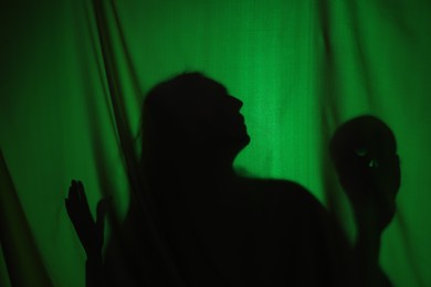 Silhouette of creepy ghost with skull behind dark green cloth