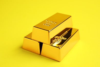Photo of Stack of shiny gold bars on yellow background