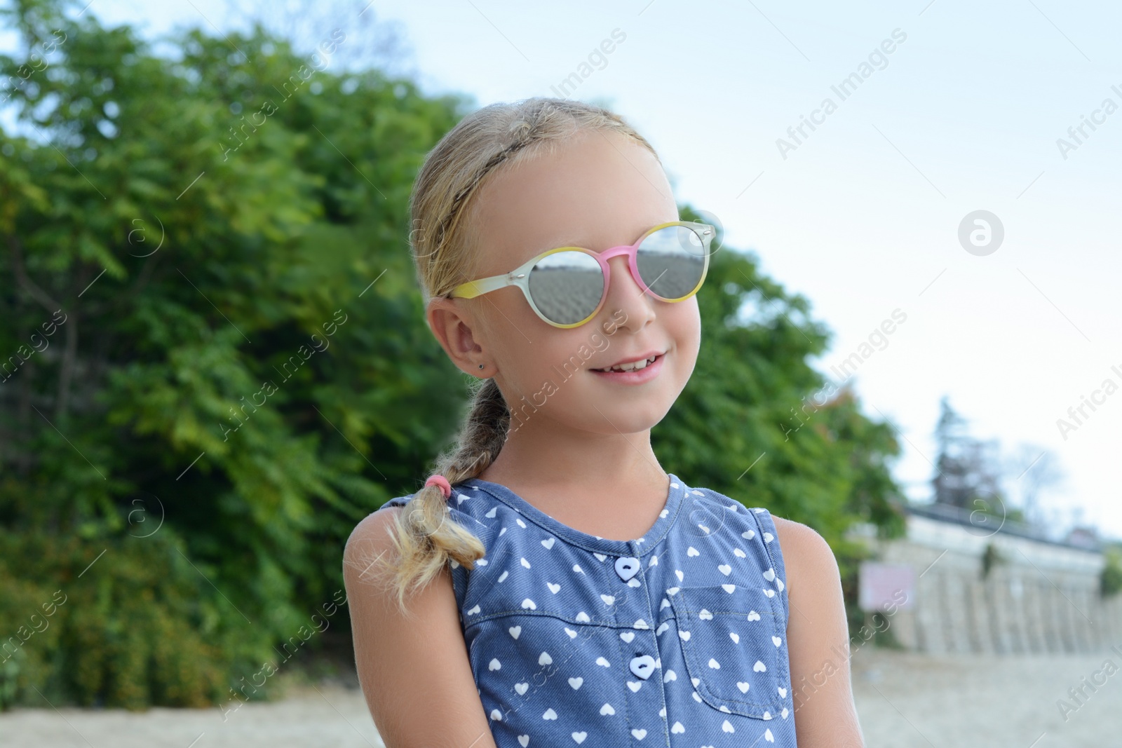 Photo of Little girl wearing sunglasses at beach on sunny day