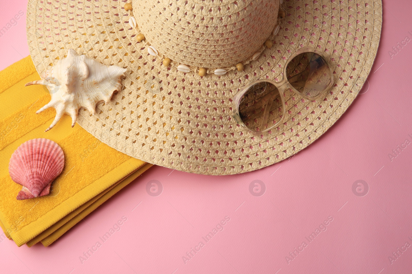Photo of Sunglasses, hat, towel and shells on pink background, flat lay with space for text. Beach accessories