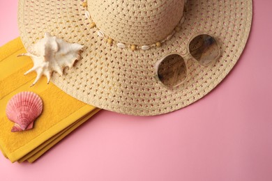 Photo of Sunglasses, hat, towel and shells on pink background, flat lay with space for text. Beach accessories